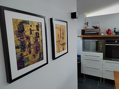 Two gold and purple abstract paintings displayed on a kitchen wall